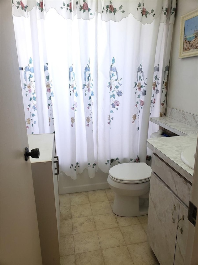 full bathroom featuring tile patterned floors, shower / bath combo with shower curtain, vanity, and toilet