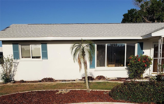 view of front of property featuring roof with shingles and stucco siding