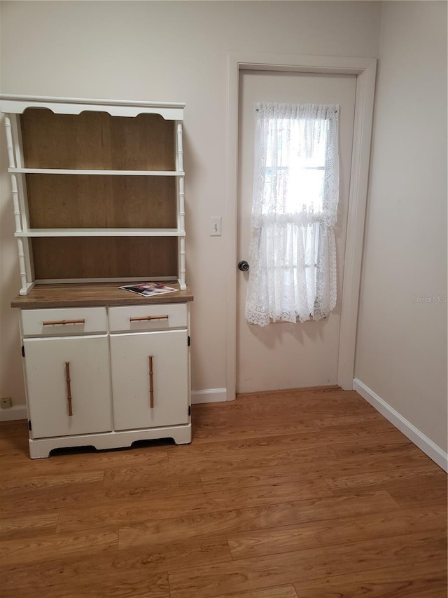 doorway featuring light wood-type flooring and baseboards