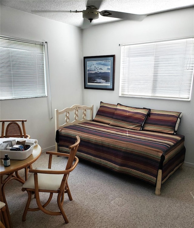 bedroom featuring carpet flooring, multiple windows, baseboards, a textured ceiling, and ceiling fan