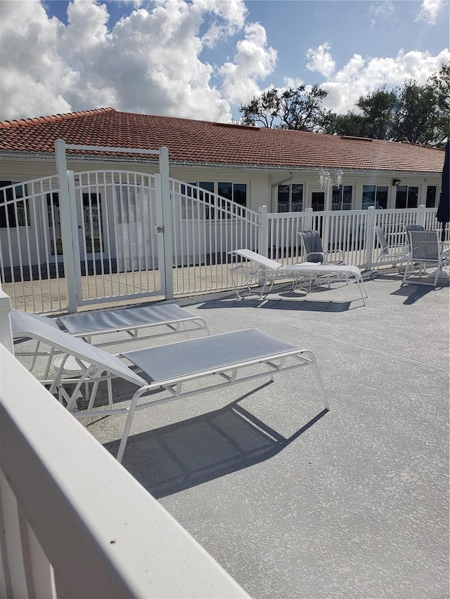 back of property featuring fence, a tile roof, and a patio