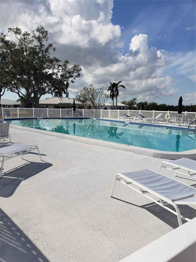 community pool with fence and a patio
