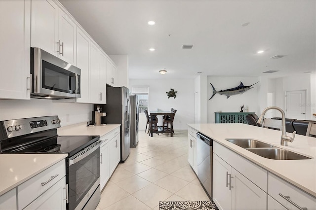 kitchen with sink, white cabinets, light tile patterned floors, and appliances with stainless steel finishes