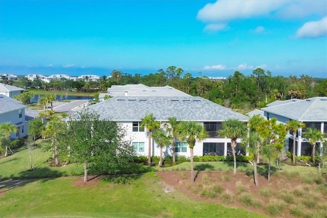 back of house with a lawn and a water view