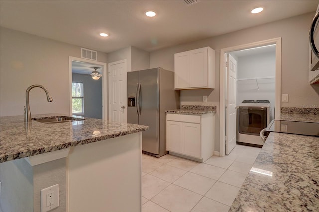 kitchen featuring light stone counters, washer / dryer, stainless steel fridge, sink, and white cabinetry