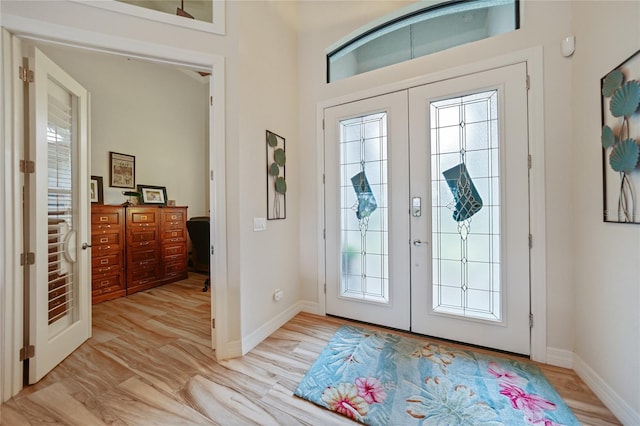 foyer entrance with french doors and light hardwood / wood-style floors