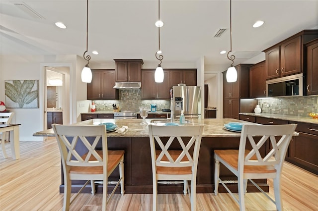 kitchen featuring hanging light fixtures, an island with sink, and stainless steel appliances