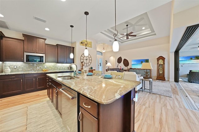 kitchen featuring tasteful backsplash, stainless steel appliances, ceiling fan, sink, and an island with sink