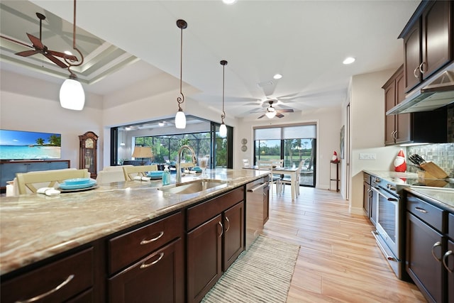 kitchen with appliances with stainless steel finishes, light wood-type flooring, dark brown cabinetry, extractor fan, and sink