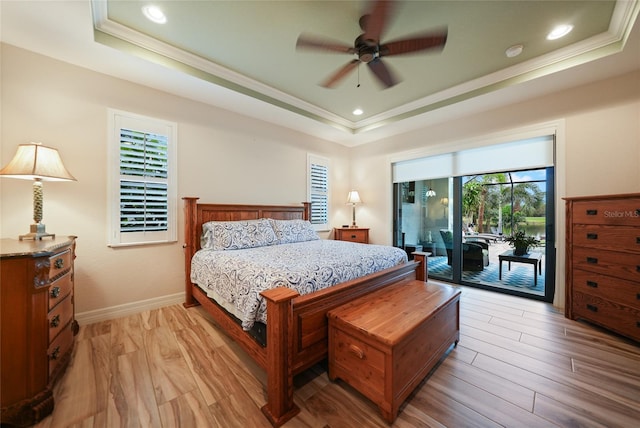 bedroom with a raised ceiling, ceiling fan, and light wood-type flooring