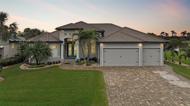 view of front of home featuring a lawn, a garage, and french doors