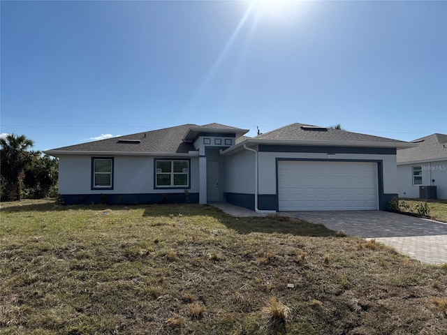 view of front facade featuring central AC unit, a garage, and a front lawn