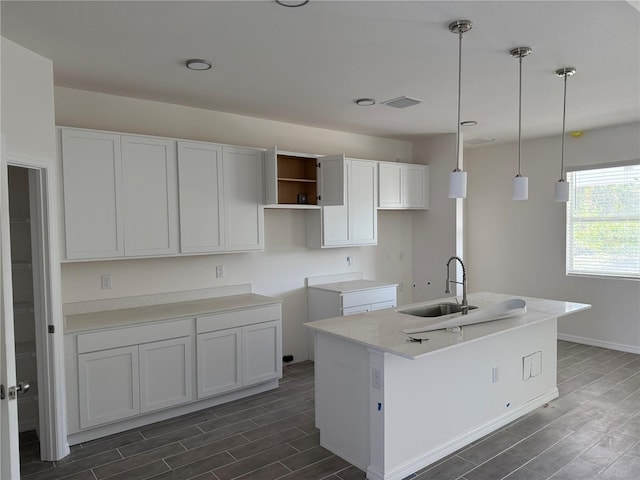 kitchen featuring white cabinetry, a kitchen island with sink, sink, and decorative light fixtures