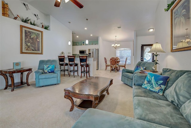 carpeted living room featuring vaulted ceiling and ceiling fan with notable chandelier