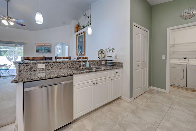 kitchen featuring sink, stainless steel dishwasher, dark stone counters, white cabinets, and washer and dryer