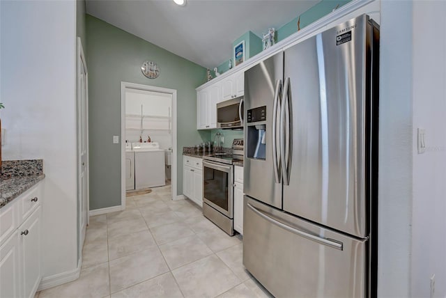 kitchen with stainless steel appliances, washer and dryer, dark stone countertops, white cabinetry, and lofted ceiling