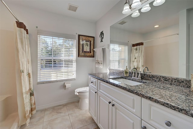 bathroom with tile patterned floors, a wealth of natural light, vanity, and toilet