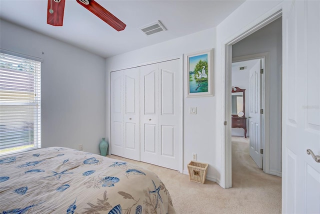 bedroom featuring ceiling fan, light colored carpet, and a closet