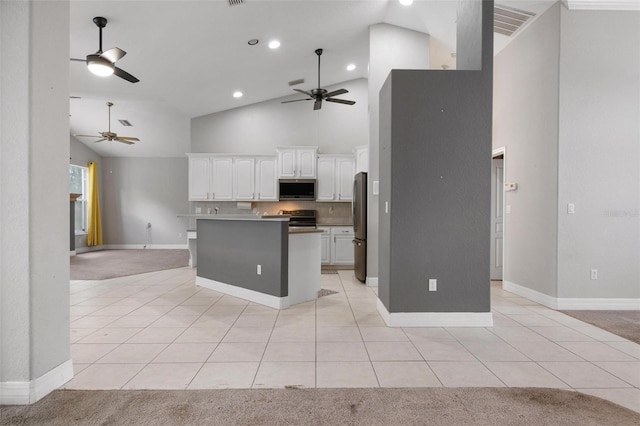 kitchen featuring white cabinets, stainless steel appliances, light colored carpet, and high vaulted ceiling