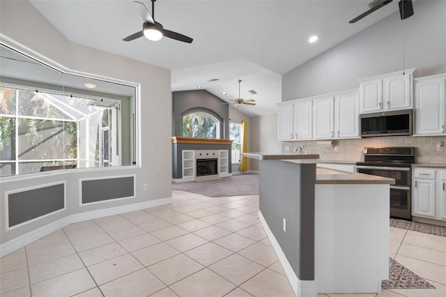 kitchen with light tile patterned flooring, white cabinetry, a fireplace, and appliances with stainless steel finishes