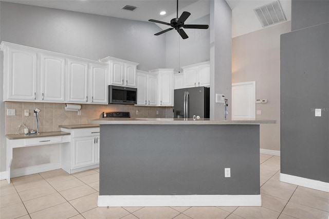 kitchen featuring white cabinets, a center island, stainless steel appliances, and high vaulted ceiling