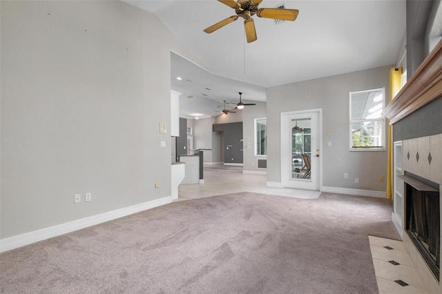 unfurnished living room with ceiling fan, a fireplace, light carpet, and vaulted ceiling