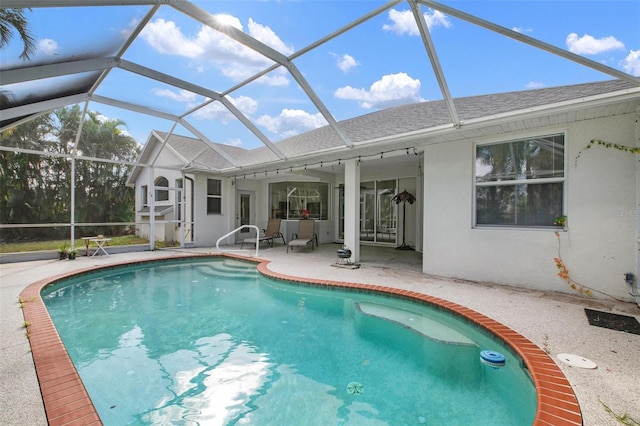 view of swimming pool featuring glass enclosure and a patio