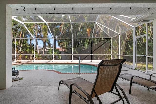 view of pool with glass enclosure and a patio area