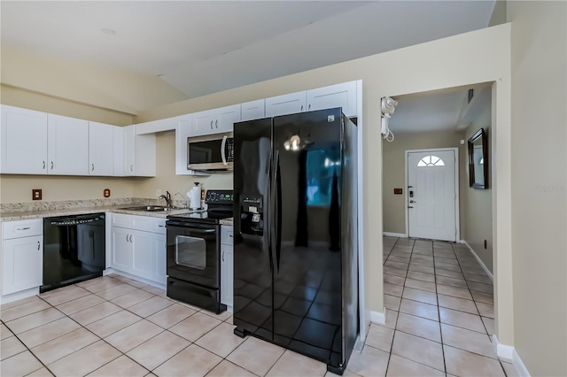 kitchen with light tile patterned floors, lofted ceiling, black appliances, white cabinets, and sink