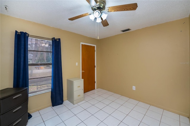 spare room with ceiling fan, a textured ceiling, and light tile patterned flooring