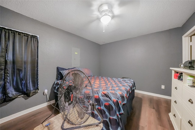 bedroom with dark hardwood / wood-style floors, ceiling fan, and a textured ceiling