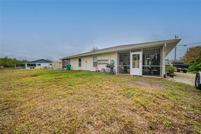 back of house with a lawn and a sunroom