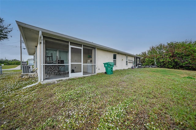 rear view of property featuring a sunroom, a yard, and central AC