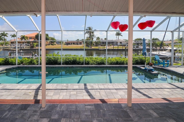 view of pool featuring glass enclosure, a patio area, and a water view