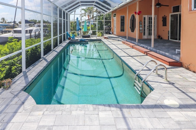 view of swimming pool featuring french doors, a patio, glass enclosure, and ceiling fan