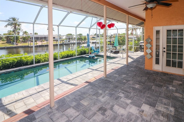 view of swimming pool with french doors, a lanai, ceiling fan, a water view, and a patio