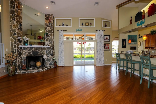 living room with high vaulted ceiling, hardwood / wood-style flooring, a stone fireplace, and ceiling fan