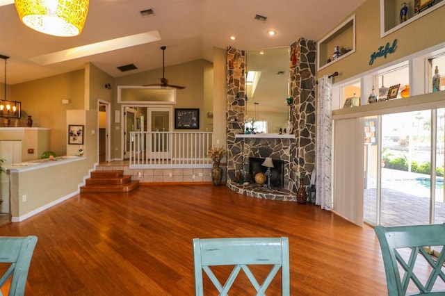 living room with a fireplace, hardwood / wood-style floors, vaulted ceiling, and ceiling fan