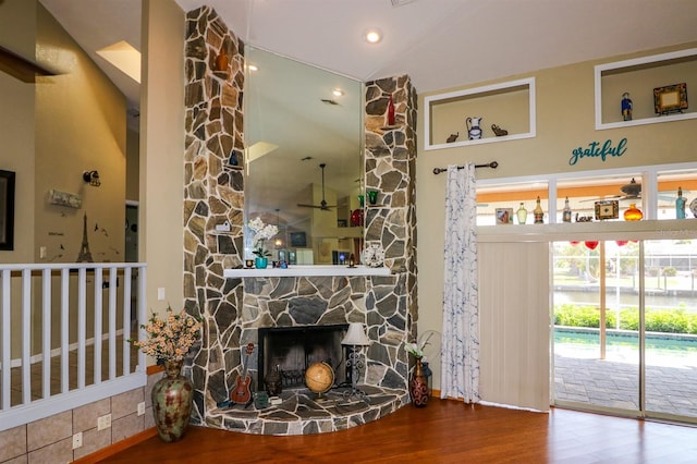 living room with a stone fireplace, ceiling fan, high vaulted ceiling, and wood-type flooring