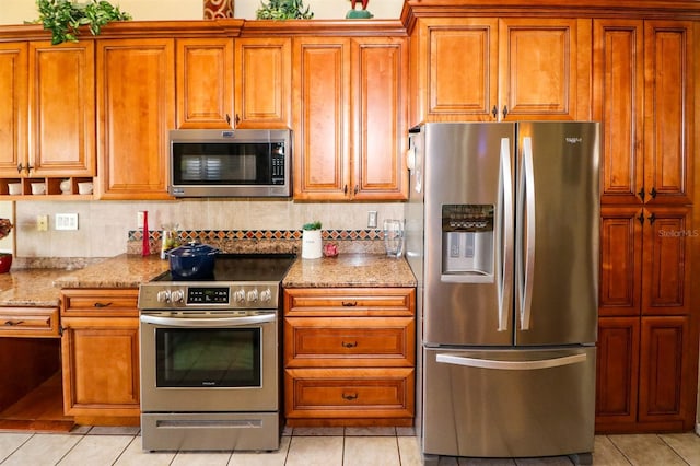 kitchen with light stone countertops, light tile patterned floors, and stainless steel appliances