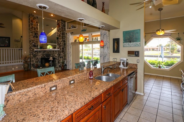 kitchen featuring stainless steel dishwasher, a stone fireplace, sink, and a wealth of natural light