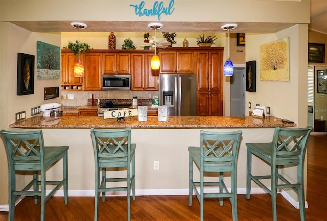 kitchen featuring kitchen peninsula, dark wood-type flooring, hanging light fixtures, and appliances with stainless steel finishes