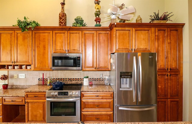 kitchen featuring ceiling fan, light stone counters, backsplash, and appliances with stainless steel finishes