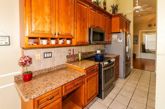 kitchen with ceiling fan, light stone countertops, tasteful backsplash, light tile patterned floors, and appliances with stainless steel finishes