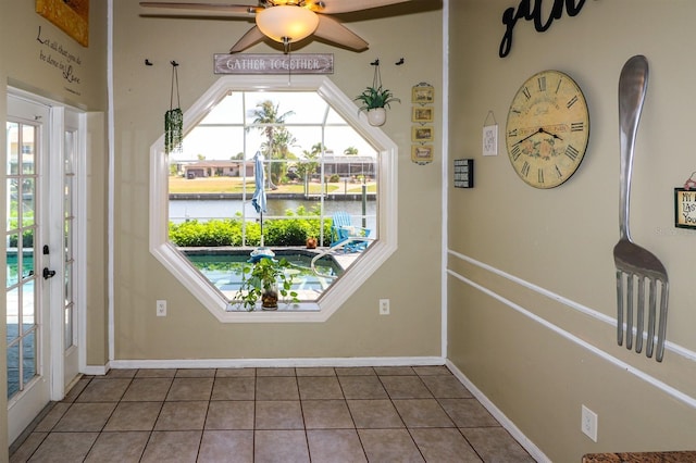 entryway with tile patterned flooring, a water view, plenty of natural light, and ceiling fan