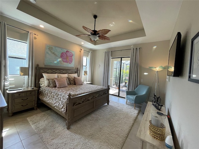 bedroom with light tile patterned floors, a tray ceiling, access to outside, and ceiling fan