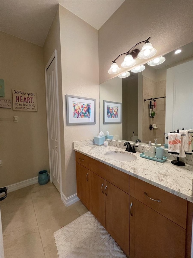 bathroom with tile patterned flooring, vanity, and tiled shower