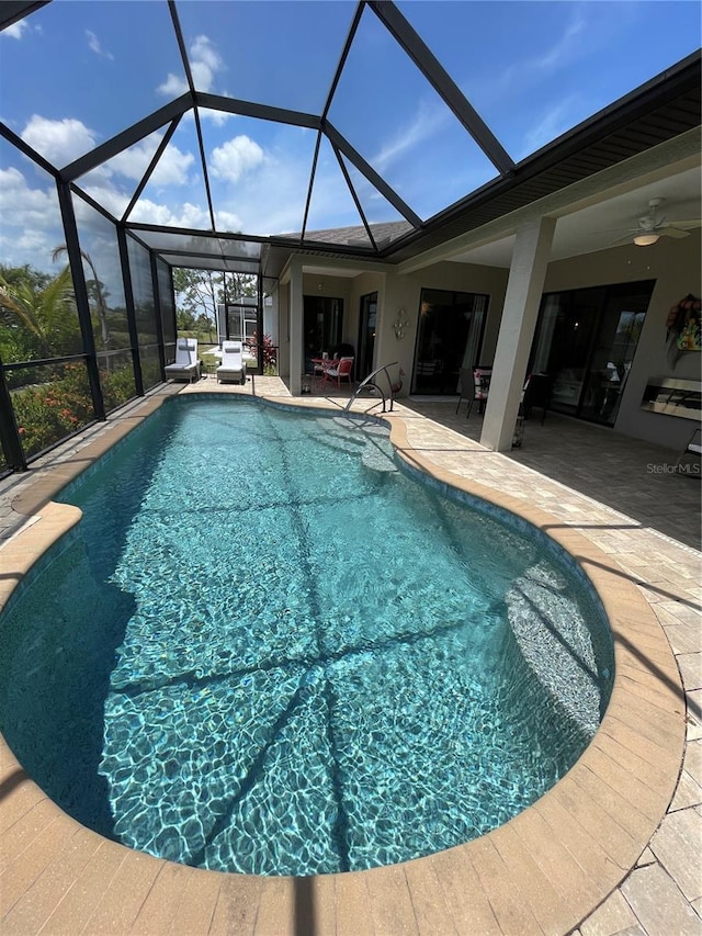 view of swimming pool featuring ceiling fan, a lanai, and a patio