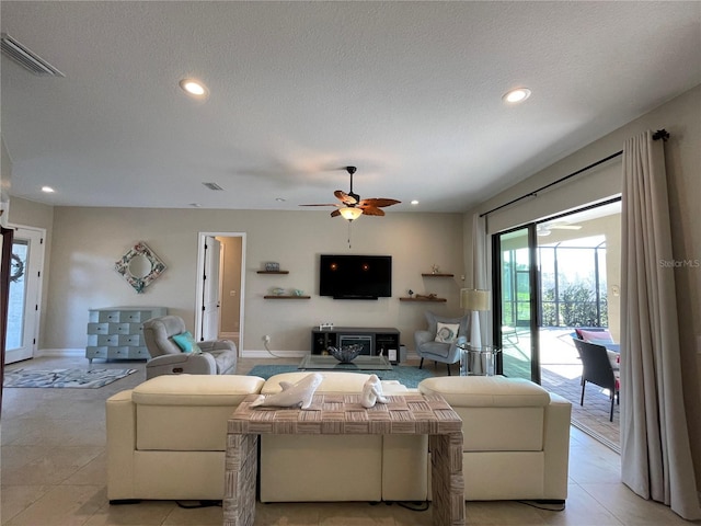 living room with ceiling fan, a textured ceiling, and light tile patterned floors