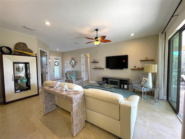 living room featuring ceiling fan, a healthy amount of sunlight, and a textured ceiling